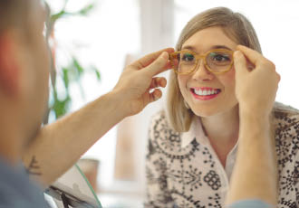 Opticien qui fait essayer des lunettes originales à une cliente